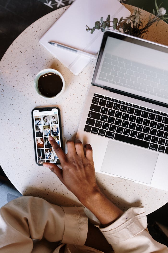 Home Person interacting with smartphone and laptop at a café table.